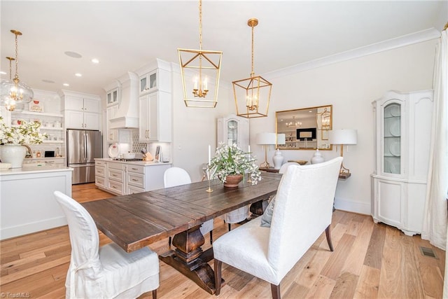 dining space with light wood-style flooring, ornamental molding, recessed lighting, an inviting chandelier, and baseboards