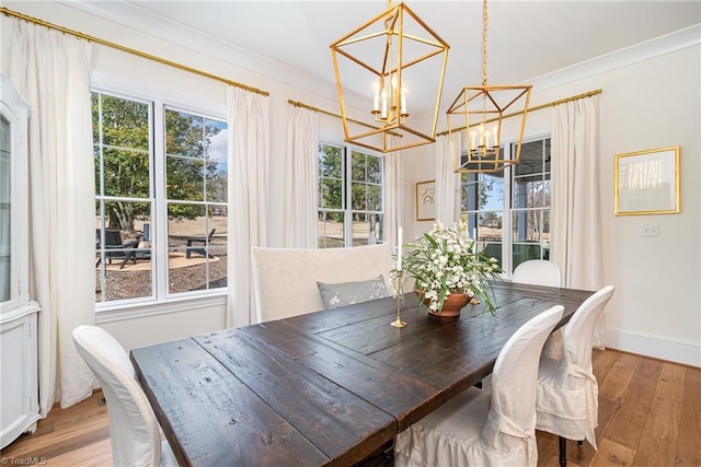 dining area with an inviting chandelier, wood finished floors, baseboards, and ornamental molding