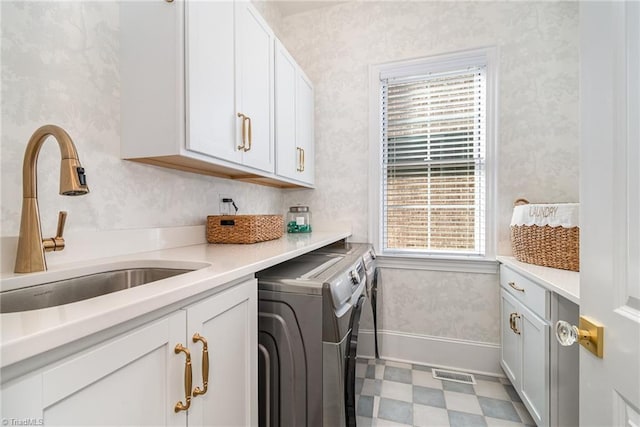 washroom featuring cabinet space, washer and dryer, wallpapered walls, and a sink