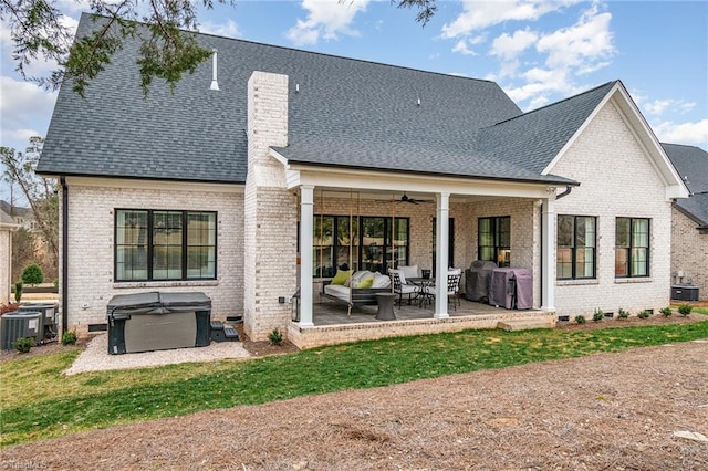 rear view of property with a ceiling fan, a patio, crawl space, brick siding, and a hot tub