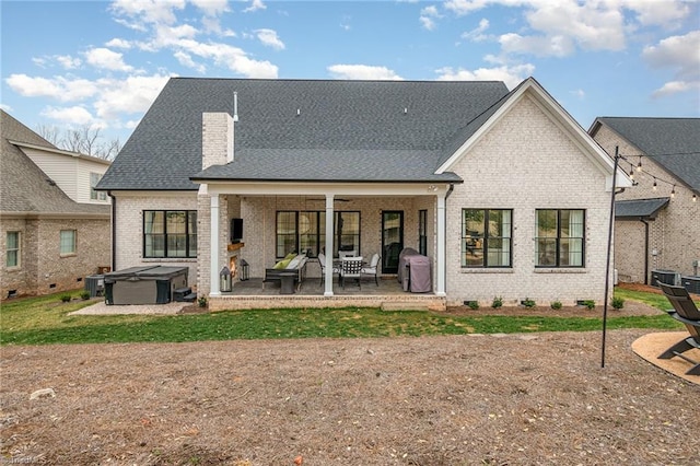 back of house with a patio, brick siding, roof with shingles, and a hot tub