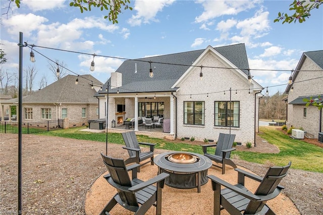 rear view of property with brick siding, a patio area, a fire pit, and fence