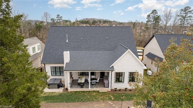 rear view of property featuring a patio area and roof with shingles