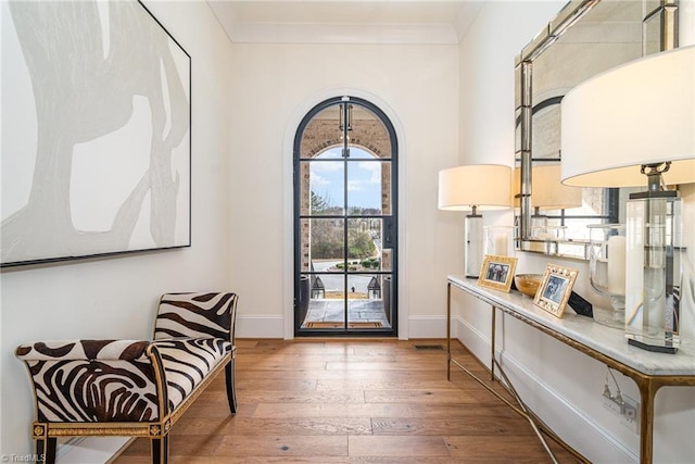 living area featuring hardwood / wood-style floors, crown molding, visible vents, and baseboards