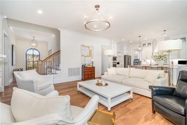 living area featuring visible vents, a chandelier, stairway, light wood-type flooring, and ornamental molding