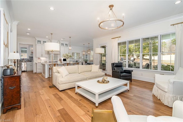 living room featuring recessed lighting, light wood-style flooring, an inviting chandelier, and ornamental molding