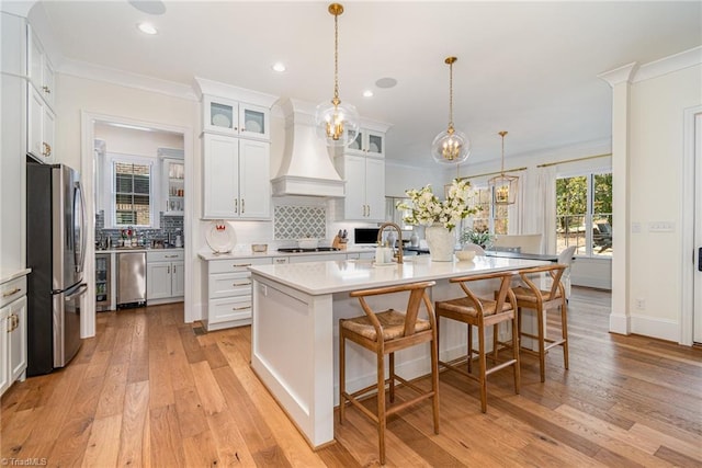 kitchen featuring tasteful backsplash, premium range hood, light countertops, ornamental molding, and stainless steel appliances