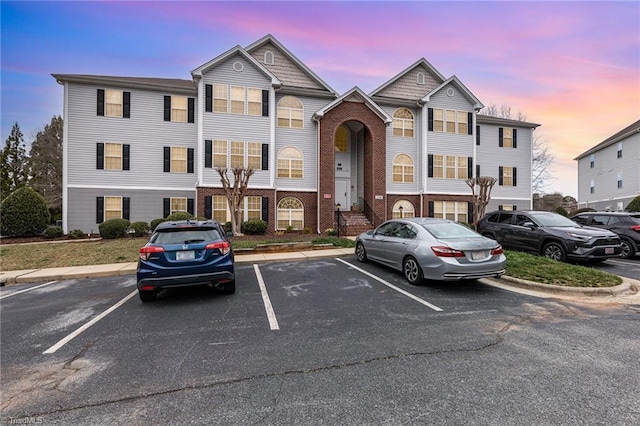 view of property featuring uncovered parking and brick siding