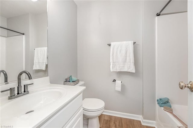 full bathroom featuring toilet, vanity, baseboards, and wood finished floors