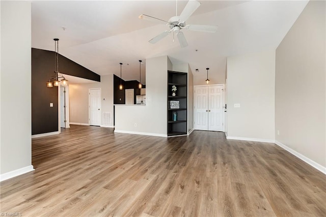 unfurnished living room with wood finished floors, baseboards, visible vents, high vaulted ceiling, and ceiling fan with notable chandelier