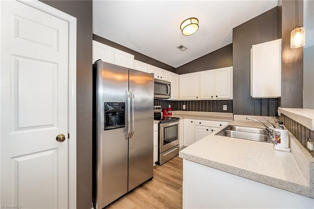 kitchen featuring light countertops, vaulted ceiling, stainless steel appliances, white cabinetry, and a sink