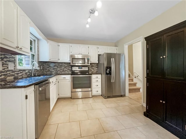 kitchen with backsplash, white cabinets, sink, light tile patterned floors, and appliances with stainless steel finishes