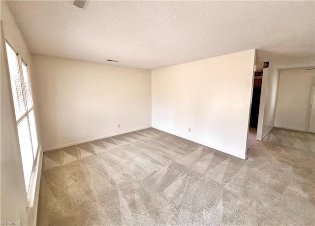 carpeted empty room with a textured ceiling