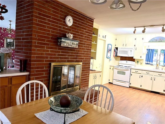 dining room featuring light wood-type flooring, sink, and a brick fireplace