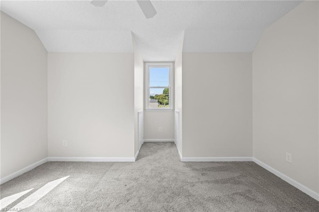 carpeted spare room featuring ceiling fan, lofted ceiling, and a textured ceiling