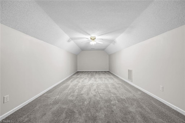 additional living space with a textured ceiling, ceiling fan, carpet flooring, and vaulted ceiling