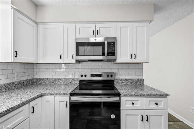 kitchen with decorative backsplash, stainless steel appliances, white cabinetry, and light stone counters