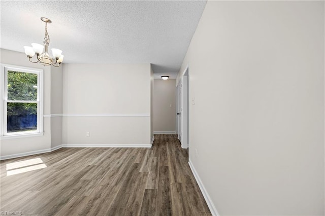 unfurnished room featuring wood-type flooring, a textured ceiling, and a notable chandelier