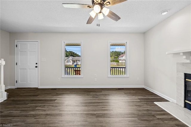 unfurnished living room with ceiling fan, dark hardwood / wood-style flooring, a high end fireplace, and a textured ceiling