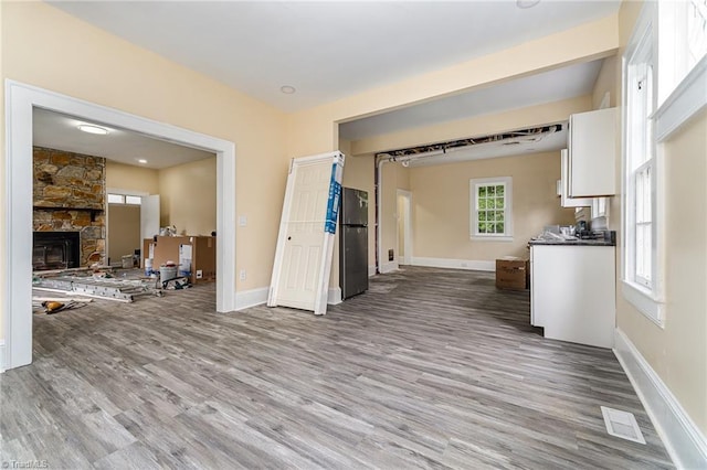 2515 N Patterson Ave, Winston-Salem, NC 27105 - unfurnished living room with wood finished floors, a stone fireplace, and baseboards