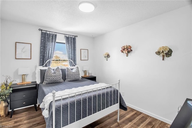 bedroom with a textured ceiling, baseboards, and wood finished floors