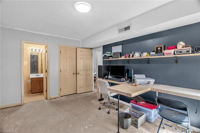 home office with a textured ceiling, unfinished concrete flooring, visible vents, and baseboards