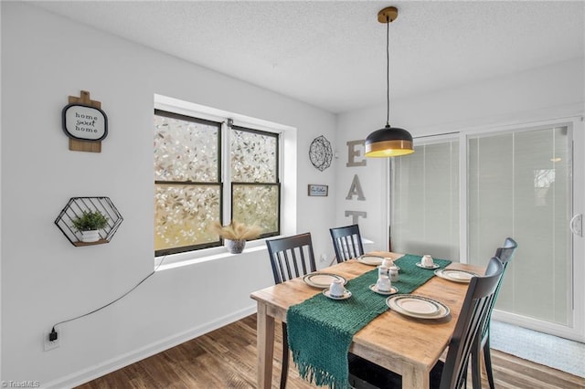 dining room with a textured ceiling, baseboards, and wood finished floors