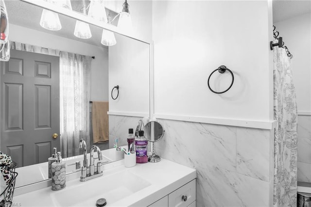 bathroom with a wainscoted wall, a textured ceiling, vanity, and tile walls