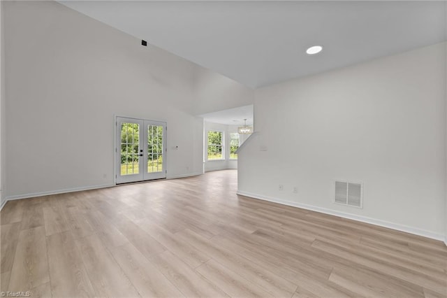 4908 Peppercorn Ln, Greensboro, NC 27406 - unfurnished living room with french doors, a chandelier, light wood-type flooring, and a high ceiling