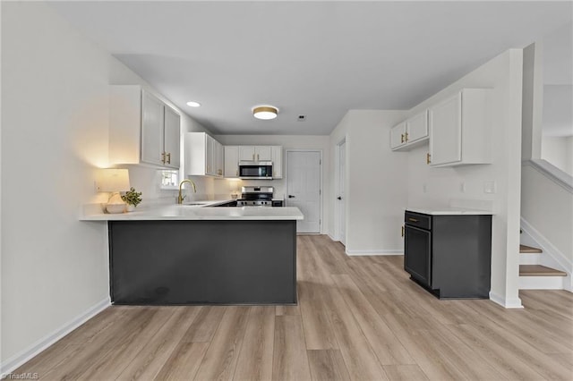 4908 Peppercorn Ln, Greensboro, NC 27406 - kitchen featuring appliances with stainless steel finishes, light wood-style flooring, light countertops, a peninsula, and recessed lighting