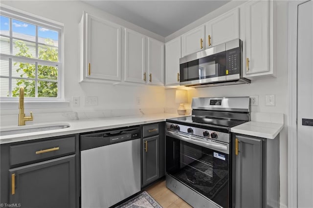 4908 Peppercorn Ln, Greensboro, NC 27406 - kitchen with appliances with stainless steel finishes, gray cabinetry, white cabinets, and light wood-style floors