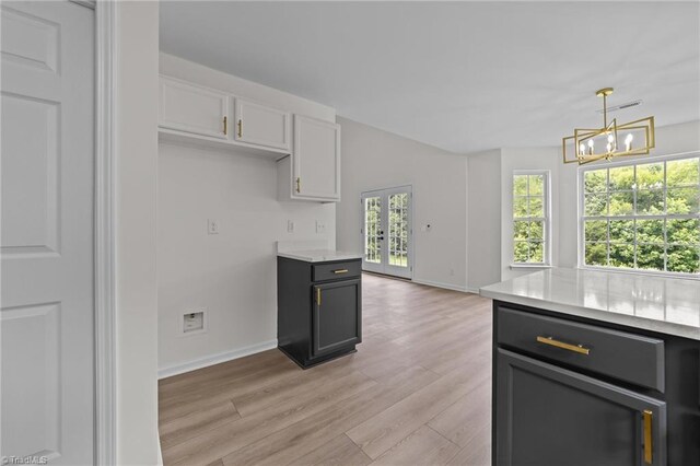 4908 Peppercorn Ln, Greensboro, NC 27406 - kitchen with a chandelier, light wood-style flooring, white cabinetry, and pendant lighting