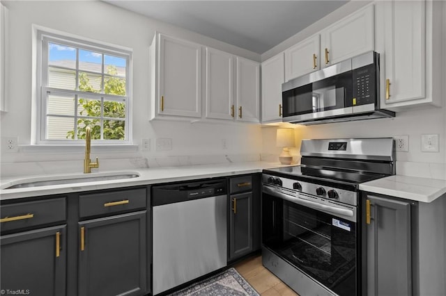 4908 Peppercorn Ln, Greensboro, NC 27406 - kitchen featuring stainless steel appliances, gray cabinets, light wood-type flooring, and white cabinetry