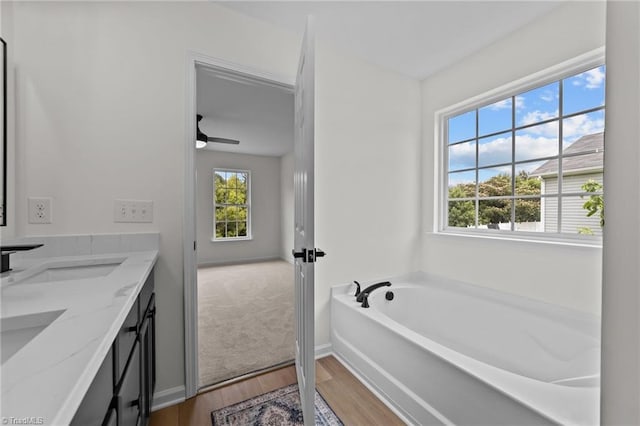 4908 Peppercorn Ln, Greensboro, NC 27406 - full bathroom with wood finished floors, double vanity, a bath, and a ceiling fan