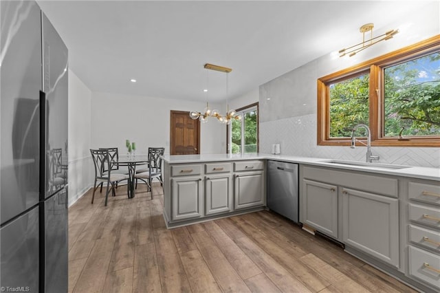 kitchen featuring stainless steel appliances, sink, light wood-type flooring, and pendant lighting