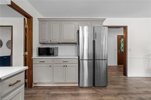 kitchen with appliances with stainless steel finishes, decorative backsplash, and dark hardwood / wood-style floors