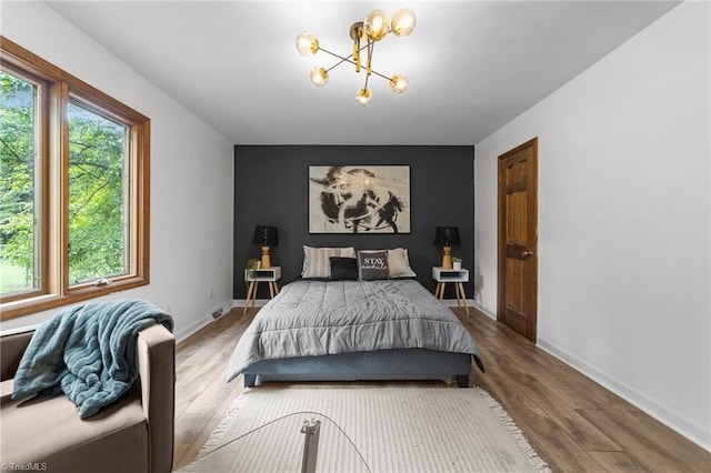 bedroom featuring wood-type flooring and an inviting chandelier