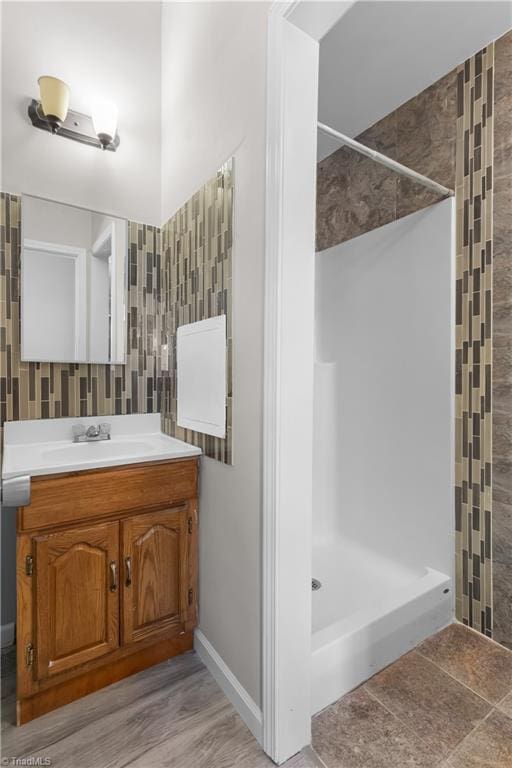 bathroom featuring a tile shower, vanity, and tile walls