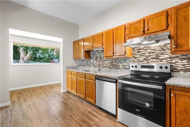 kitchen featuring light stone counters, light hardwood / wood-style floors, tasteful backsplash, sink, and stainless steel appliances