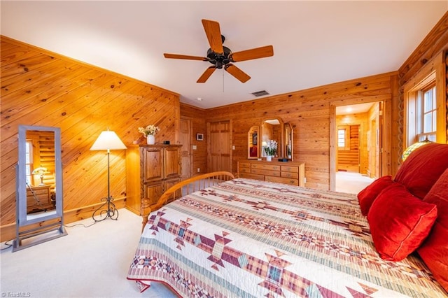 bedroom with ceiling fan, wood walls, and light carpet