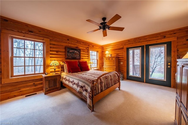 bedroom featuring light carpet, rustic walls, ceiling fan, and access to outside