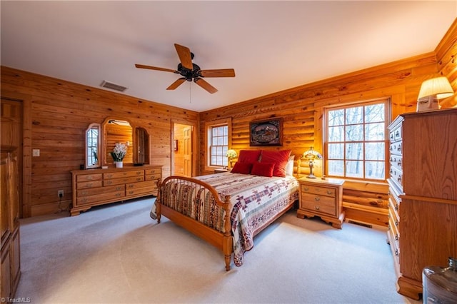 carpeted bedroom with ceiling fan and rustic walls