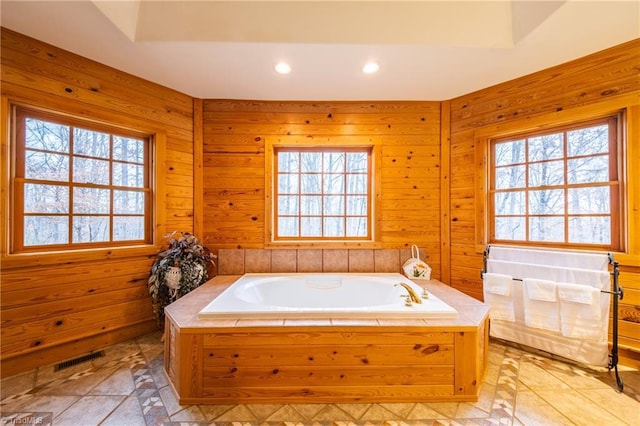 bathroom with tiled bath and wood walls