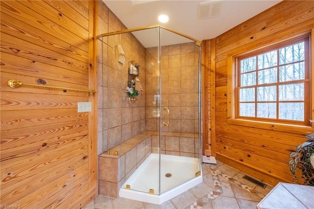 bathroom featuring wood walls, tile patterned floors, and a shower with door