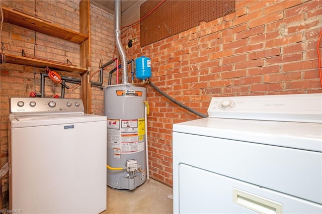 washroom with washer and clothes dryer, water heater, and brick wall