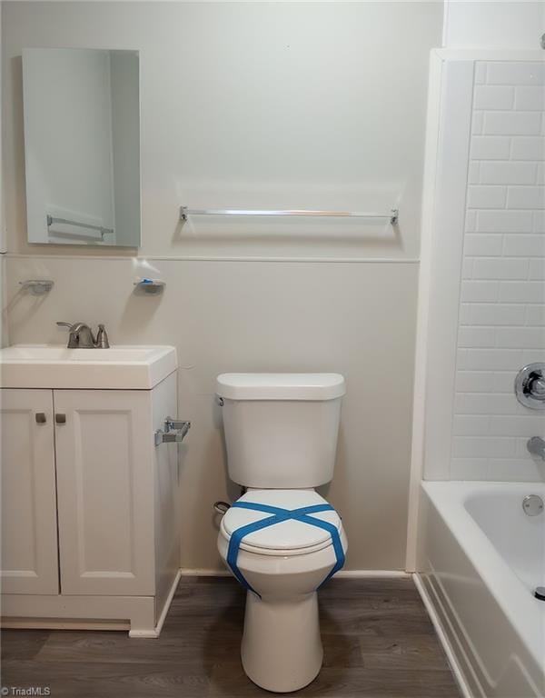 full bathroom with wood-type flooring, toilet,  shower combination, and vanity