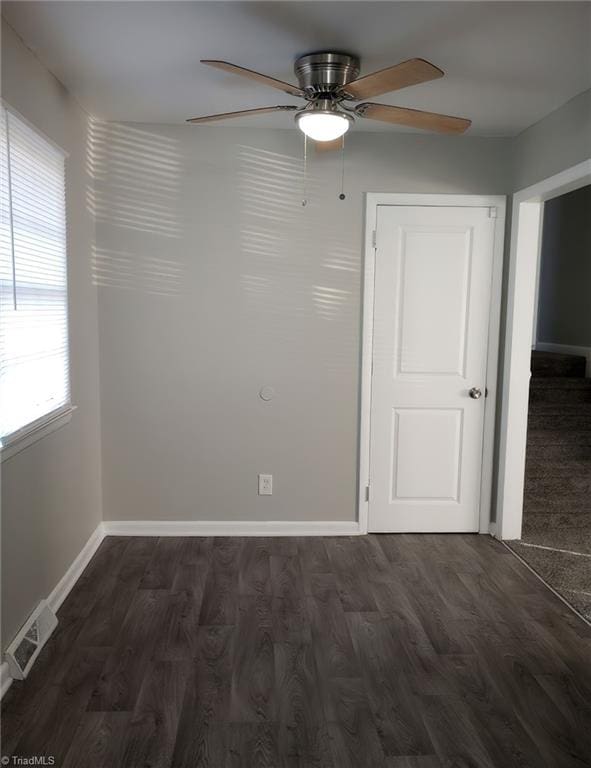 unfurnished room featuring dark wood-type flooring and ceiling fan