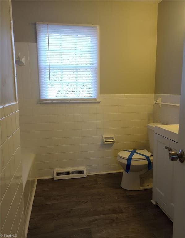 bathroom featuring vanity, hardwood / wood-style flooring, tile walls, and toilet