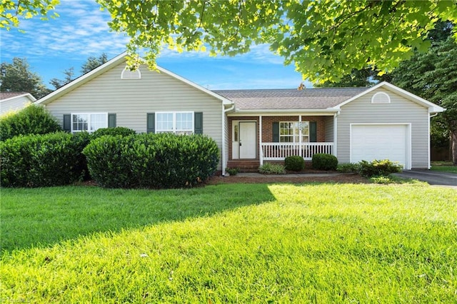 ranch-style house featuring a front lawn, covered porch, and a garage