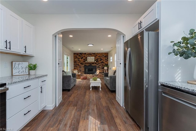 kitchen with arched walkways, dark wood-style flooring, open floor plan, and stainless steel fridge with ice dispenser